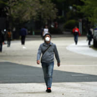 A man wearing a mask walks in a park in Tokyo on April 22. | AP