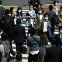 People with protective masks use a pedestrian crossing Thursday in Tokyo. | AP