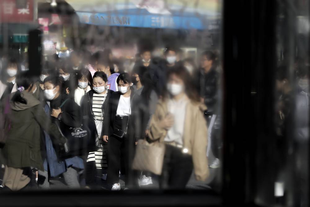 Correcting misinformation: Pedestrians wearing protective masks walk along a street in Tokyo's Shibuya district in March. | BLOOMBERG
