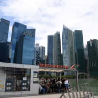 Visitors wait for a boat tour in Singapore, with the city\'s financial district in the background. | AFP-JIJI