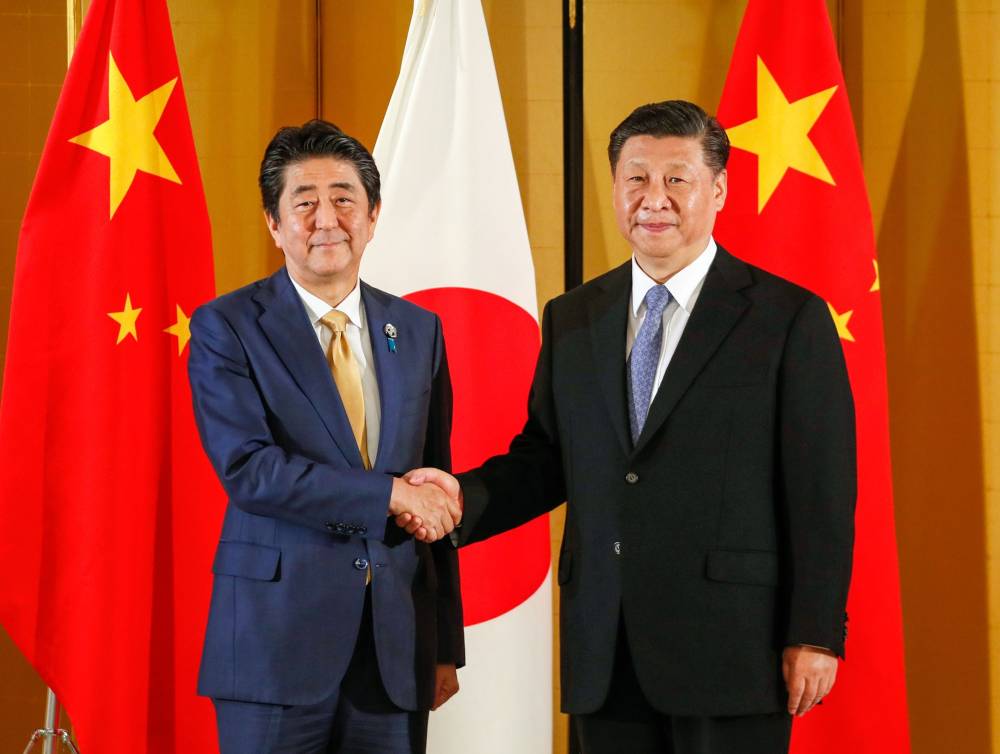 Prime Minister Shinzo Abe shakes hands with Chinese President Xi Jinping during a bilateral meeting ahead of the Group of 20 summit in Osaka last June. Abe has refrained from blaming China for the COVID-19 crisis. | BLOOMBERG