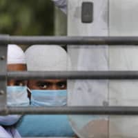 Muslim pilgrims wait in bus that will take them to a quarantine facility amid concerns over the spread of the new coronavirus, in the Nizamuddin area of New Delhi on Tuesday. | AP