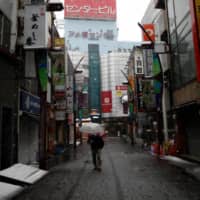 A man wearing a protective face mask walks down an empty street at Ameyoko shopping and amusement district in Tokyo during the first weekend after Gov. Yuriko Koike urged residents to stay indoors in a bid to keep the coronavirus disease from spreading. | RUETERS