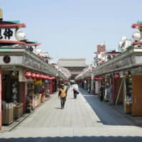 A handful of people walk on a famous shopping street in Tokyo\'s Asakusa area on Saturday, after the metropolitan government asked citizens to refrain from leaving their homes this weekend to prevent the further spread of the new coronavirus. | KYODO