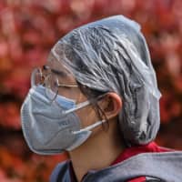 A woman wearing protective gear walks near the Hankou railway station in Wuhan, China, on Saturday. | AFP-JIJI