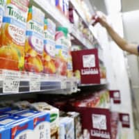 Stocking up: A convenience store worker checks merchandise at a shop in Japan. Customer spending helped boost sales at the nation\'s convenience stores as people prepared to stay home more because of the spread of COVID-19. | KYODO
