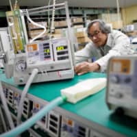 Metran Co. Chairman and CEO Kazufuku Nitta works with a Compos X ventilator, which was originally developed for animals but can also be used on human COVID-19 patients, at its factory in Kawaguchi, Saitama Prefecture, last week. | REUTERS