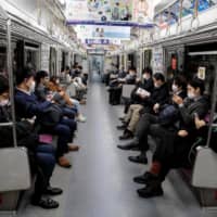 People wearing face masks amid concerns over the spread of the COVID-19 coronavirus, commute on a train in Tokyo on Monday.  | AFP-JIJI
