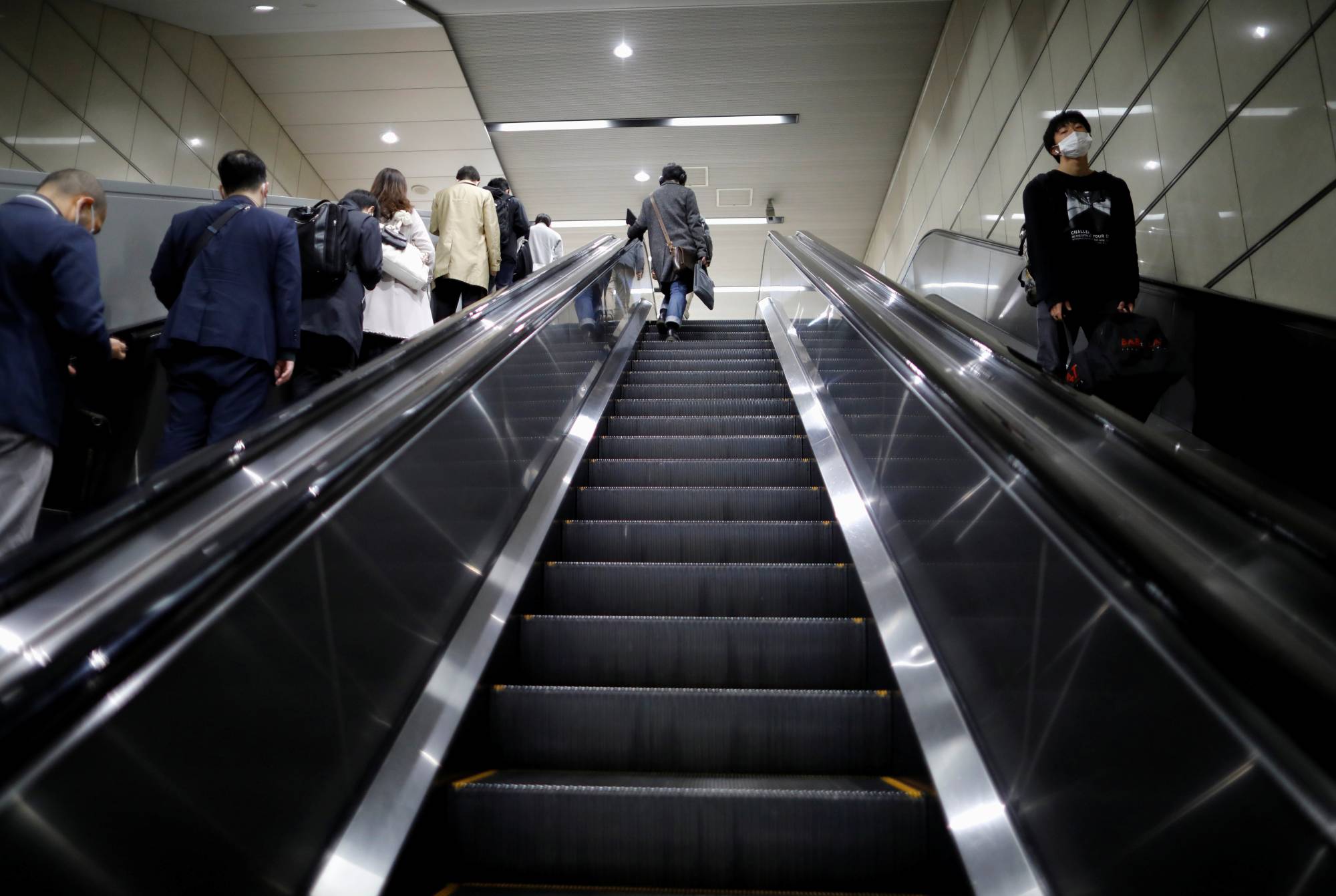Passengers wearing masks head to work at a train station in Tokyo on Monday. | REUTERS