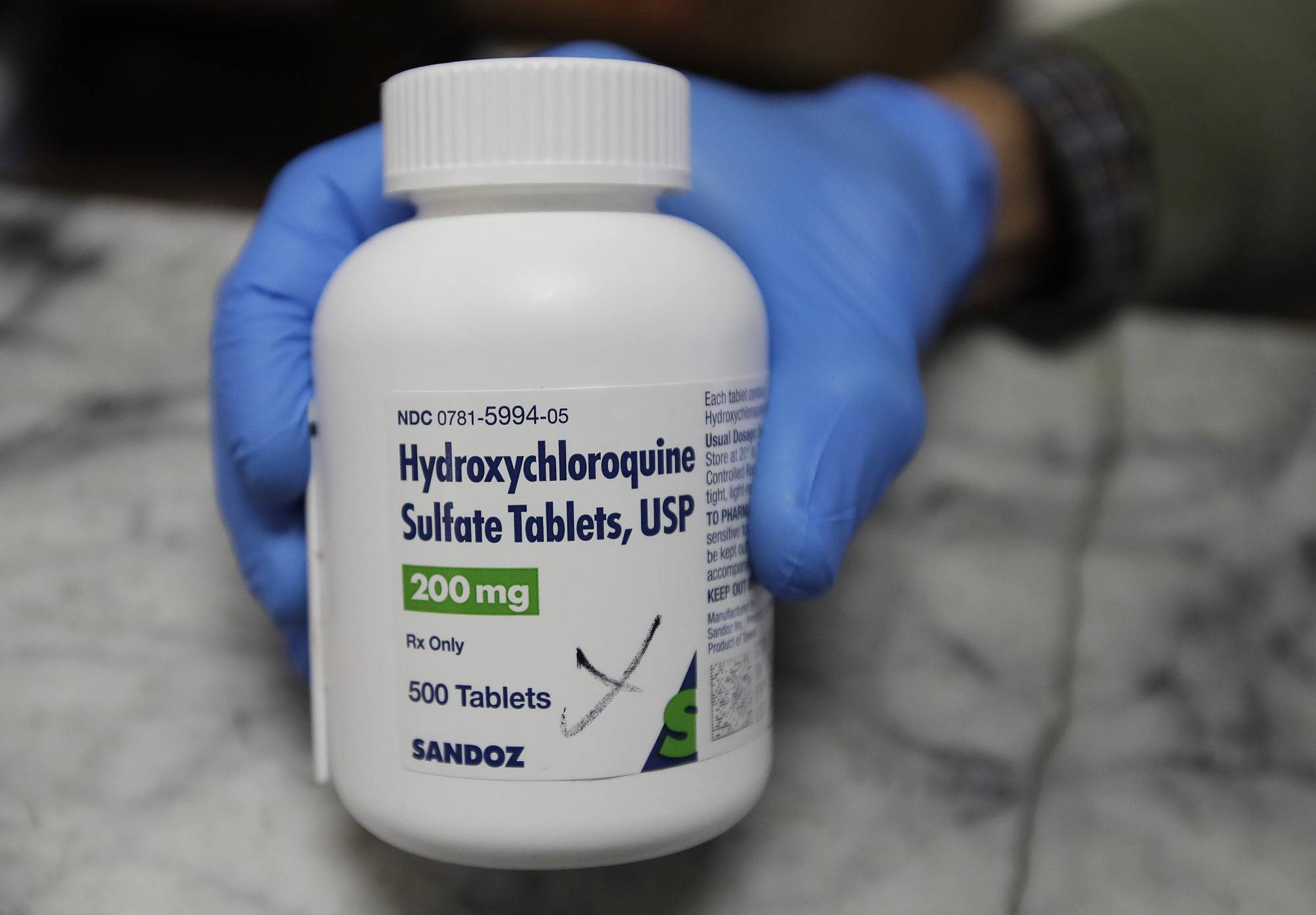 A pharmacist holds a bottle of the drug hydroxychloroquine in Oakland, California, on Monday. | AP