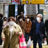 People wearing face masks walk inside JR Gotanda Station in Tokyo on Tuesday. | AFP-JIJI