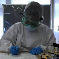 Extra caution: A doctor at the Self-Defense Forces Central Hospital in Tokyo looks over Joe Oliver\'s paperwork.  | JOE OLIVER
