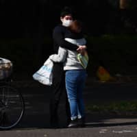A couple hug at the entrance of Yoyogi Park in Tokyo on Saturday. The Tokyo Metropolitan Government confirmed more than 190 new COVID-19 infections on Saturday, setting yet another single-day record.  | AFP-JIJI