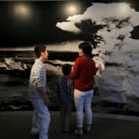 A family looks at a photograph of the A-bomb\'s mushroom cloud at the Hiroshima Peace Memorial Museum in March 2015. | REUTERS