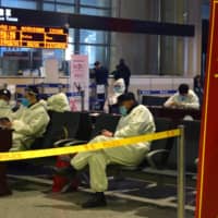 Police officers in protective suits sit at an aiport in Harbin, the capital of China\'s Heilongjiang province bordering Russia, following the spread of COVID-19 on Saturday.  | REUTERS