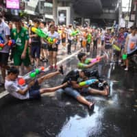 This combination photo shows revelers using toy water guns to spray at one another as they celebrate the Buddhist New Year, known in Thailand as Songkran, in Bangkok on April 14, 2019, and the same place Monday after the government banned Songkran festivities over the coronavirus pandemic. | AFP-JIJI