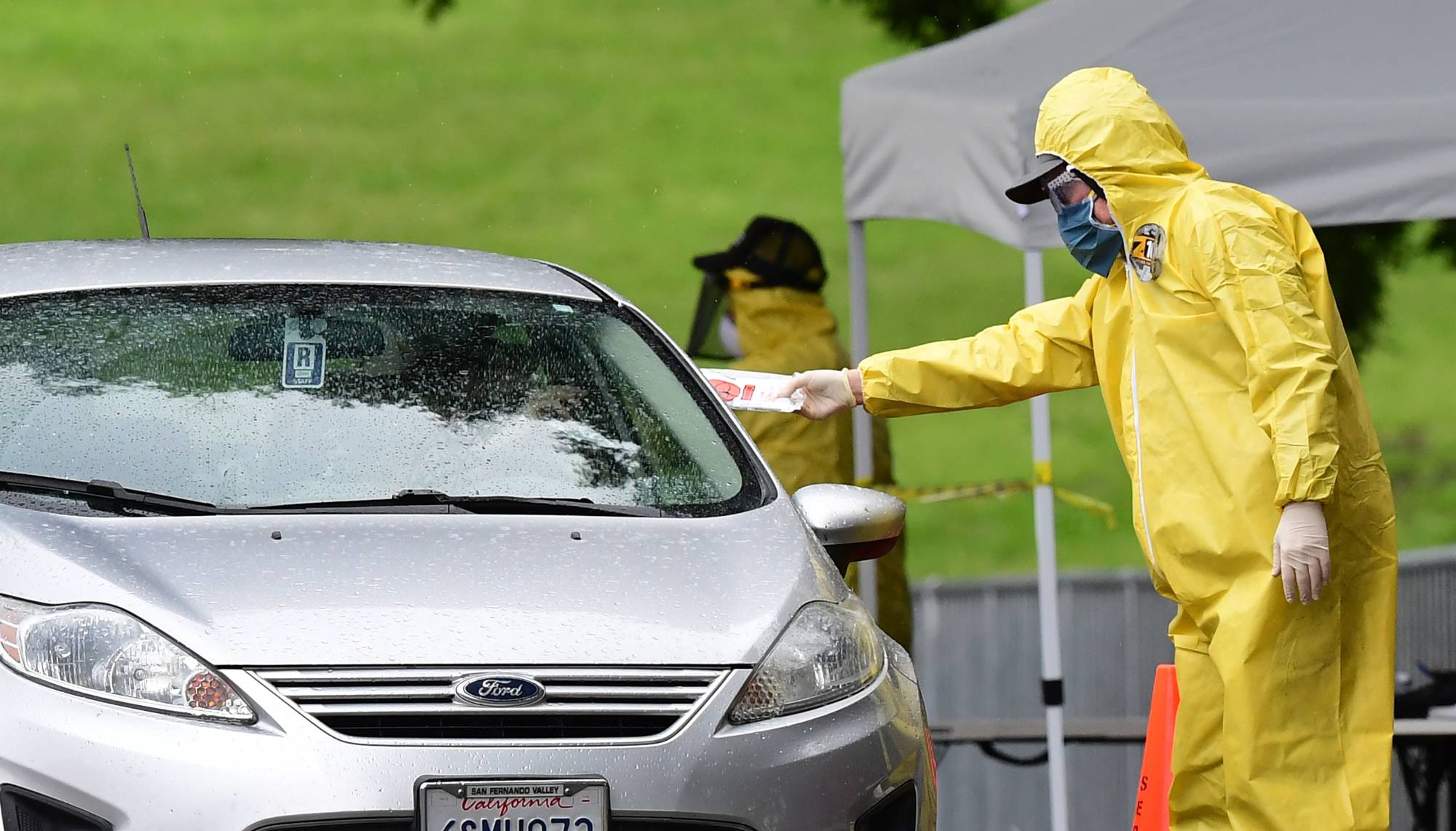 A driver receives a COVID-19 test kit at a coronavirus mobile testing site at Lincoln Park in Los Angeles, California on Thursday as COVID-19 antibody testing begins at undiscolsed locations across Los Angeles County. | AFP-JIJI