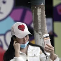 A woman lowers her mask briefly for a selfie in Wuhan, in central China\'s Hubei province, on Monday. | AP