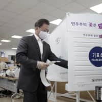 South Korean President Moon Jae-in enters a voting booth to cast his early vote for the parliamentary election at a polling station in Seoul on Friday. | YONHAP / VIA AP
