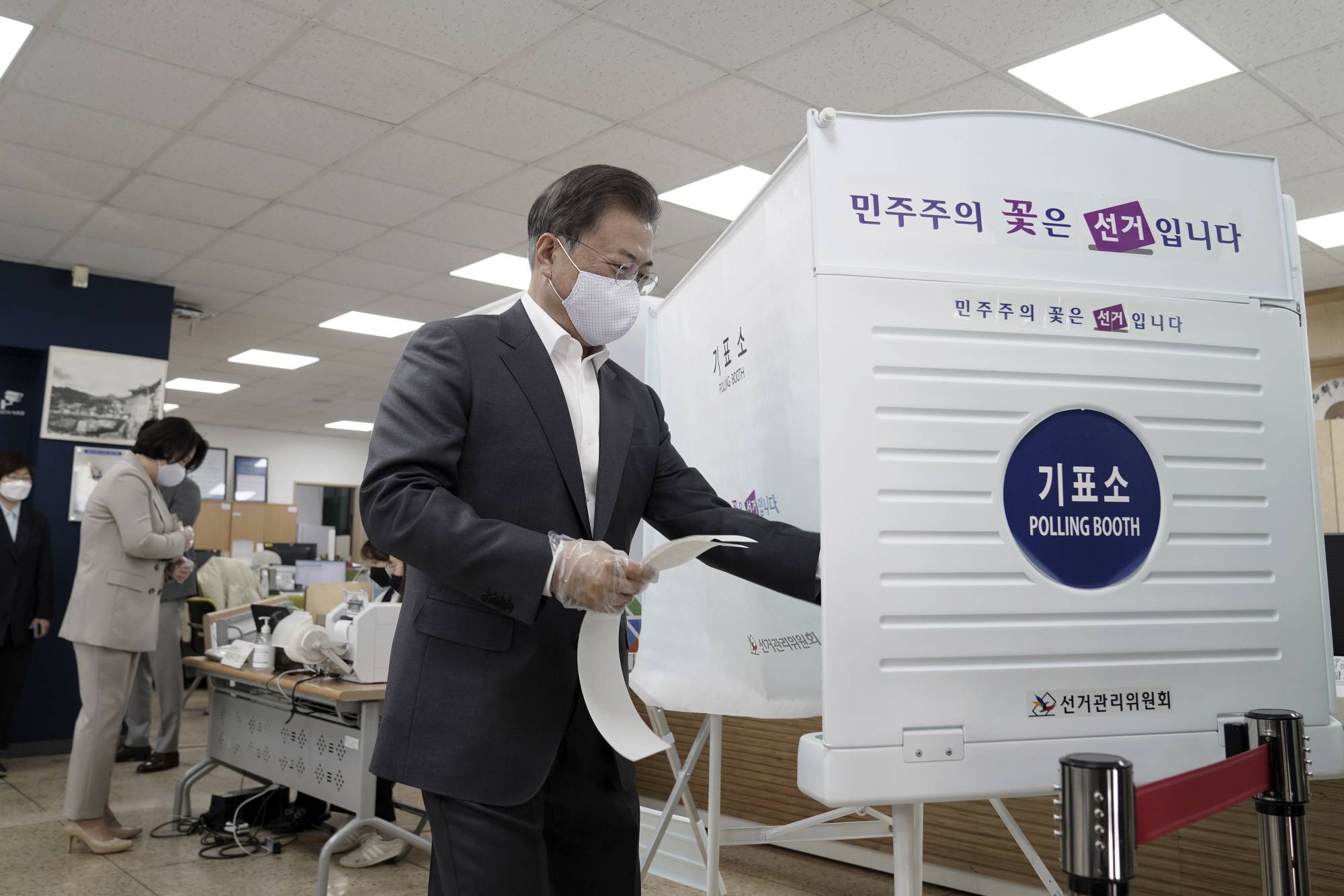 South Korean President Moon Jae-in enters a voting booth to cast his early vote for the parliamentary election at a polling station in Seoul on Friday. | YONHAP / VIA AP