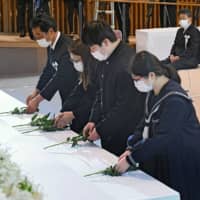 Katsunori Uchimura (left) and his family offer flowers at a ceremony in the city of Kumamoto on Tuesday, marking the fourth anniversary of two massive earthquakes in the prefecture. | POOL / VIA KYODO