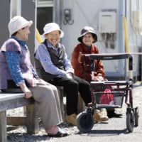 A group of elderly women sit on a bench for a chat in Mashiki, Kumamoto Prefecture. | KYODO
