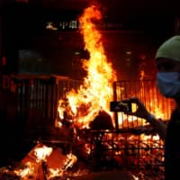 A protester films a fire at the entrance to MTR Central Station in Hong Kong in September. | REUTERS