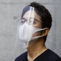 Tokujin Yoshioka, who designed the torches for the Tokyo Olympic and Paralympic relays, wears a homemade face shield he created.  | TOKUJIN YOSHIOKA / VIA KYODO