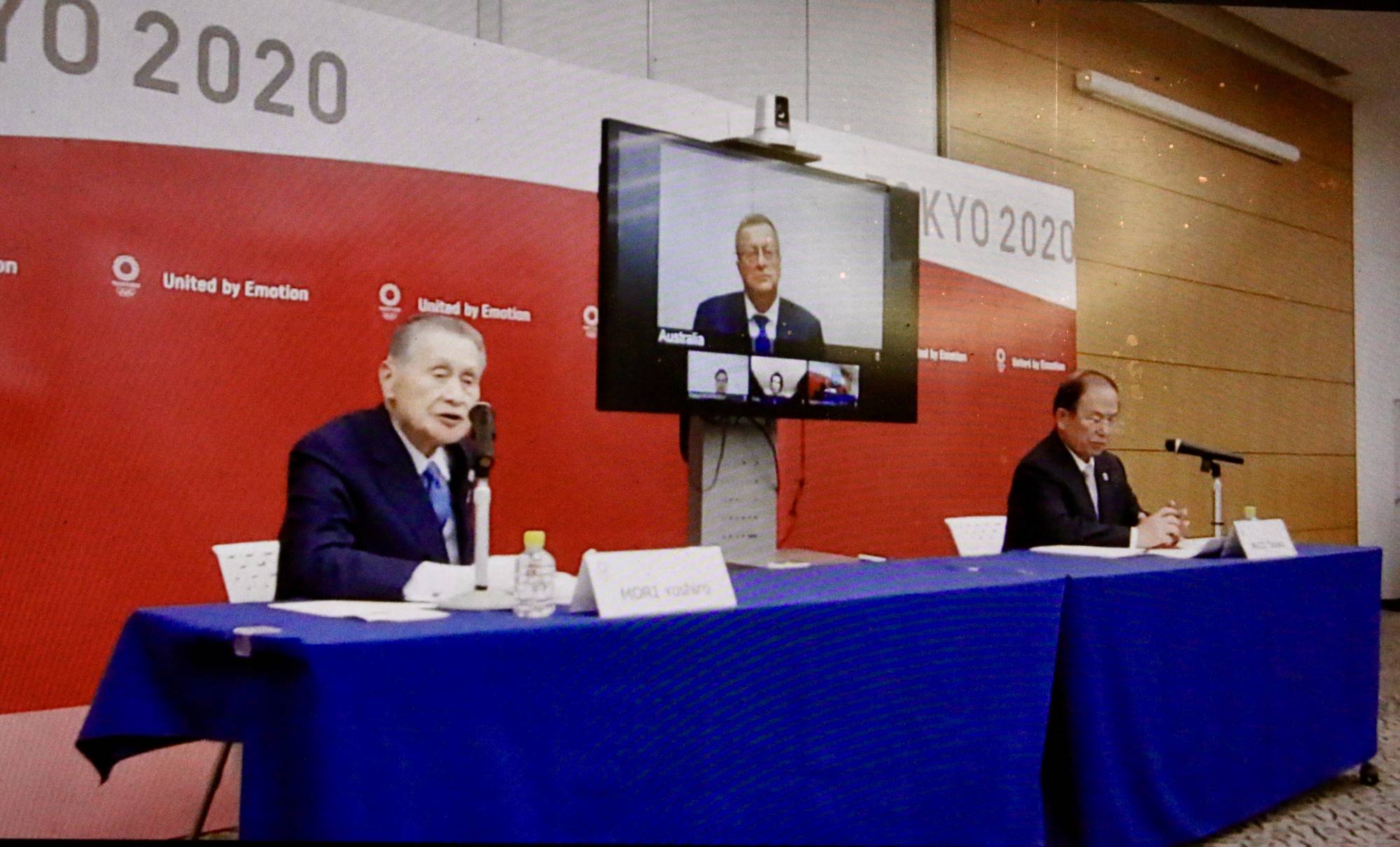 Yoshiro Mori (left), president of the organizing committee for the Tokyo Olympics and Paralympics, speaks during an online video news conference also attended by organizing committee CEO Toshiro Muto (right) and IOC Coordination Commission chair John Coates (on screen) on Thursday. | KAZ NAGATSUKA