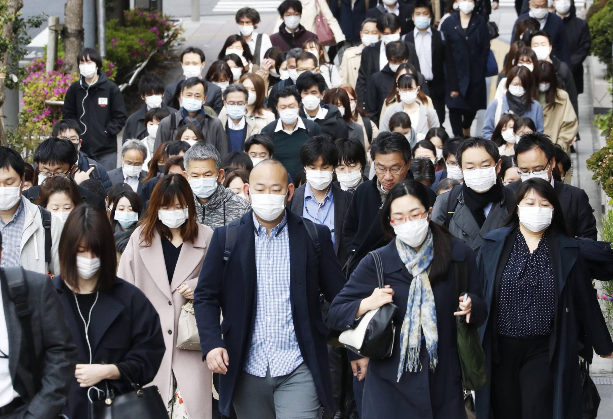 People wearing face masks head to work in Tokyo's Chuo Ward on Friday amid the spread of the new coronavirus. | KYODO