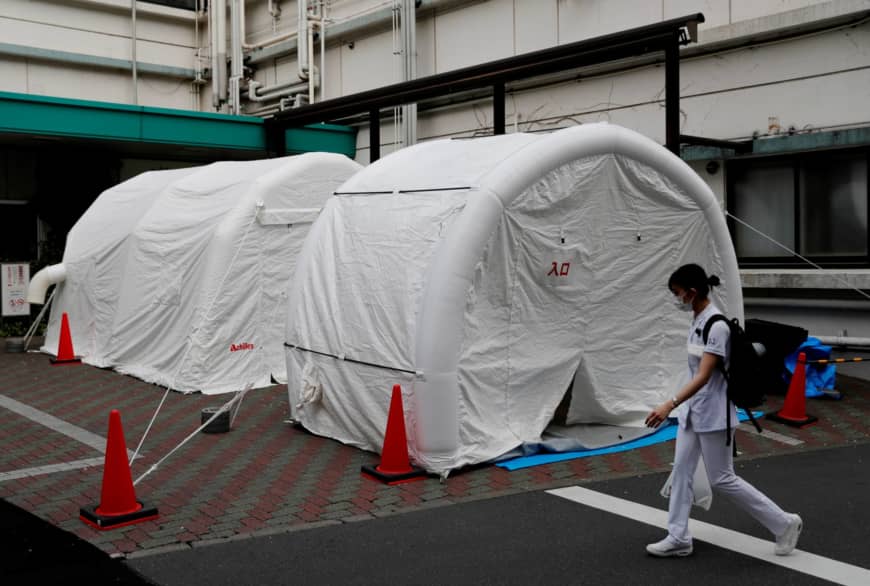 A medical worker walks by tents set up to test for the new coronavirus at Kawakita General Hospital in Tokyo on Friday. | REUTERS