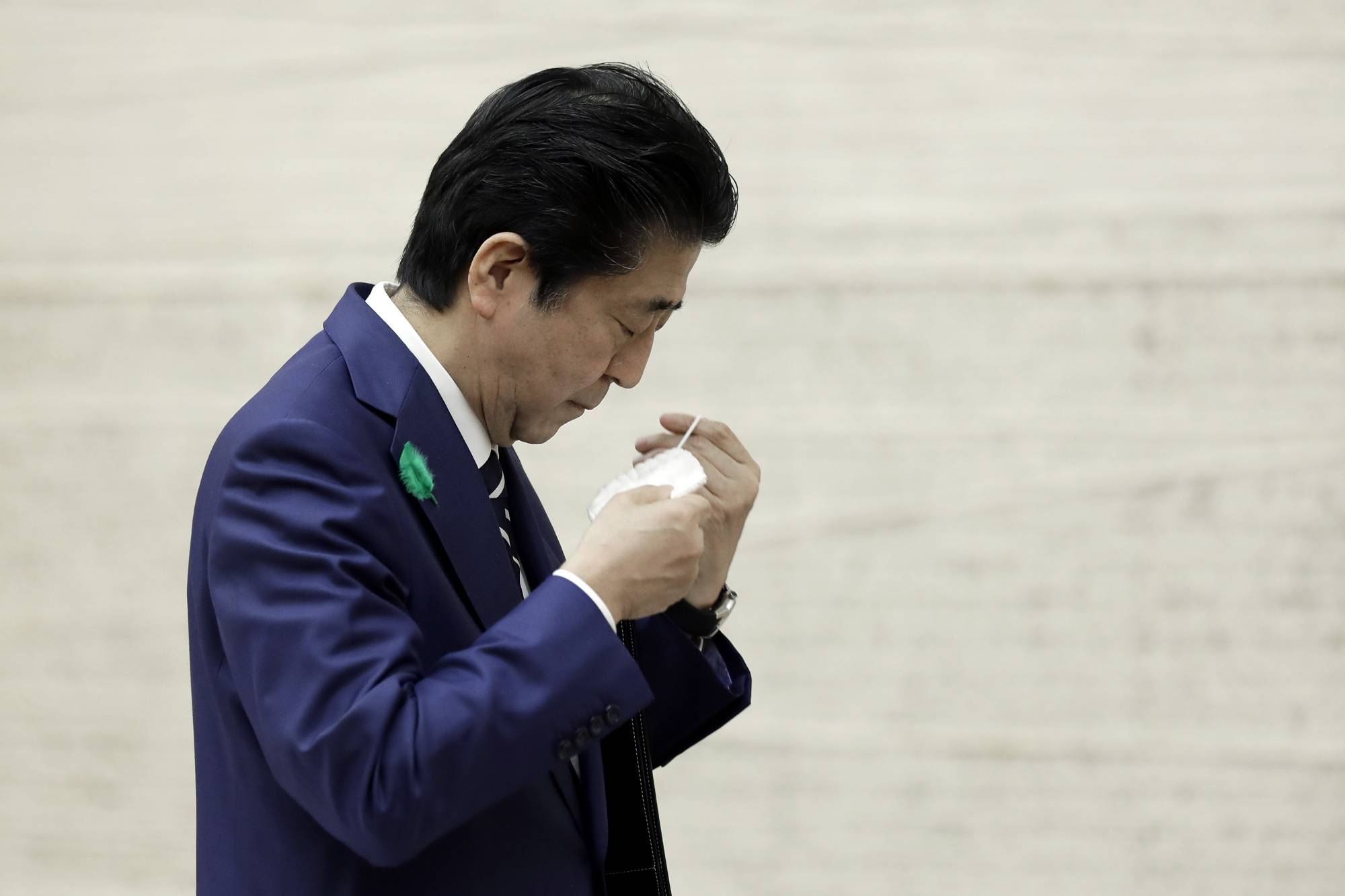 Prime Minister Shinzo Abe puts on a protective mask as he departs a news conference in Tokyo on Friday. | BLOOMBERG