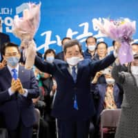 Lee Nak-yon, South Korea\'s former prime minister, and his wife, Kim Suk-hee, hold flowers in a sign of victory in the parliamentary elections at his office in Seoul on April 15. | YONHAP / VIA AFP-JIJI