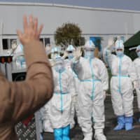 Medical personnel wave to a patient being discharged from the Leishenshan Hospital after recovering from the novel coronavirus in Wuhan, China, on March 1.  | CHINA DAILY / VIA REUTERS 