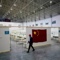 A volunteer walks inside a convention center that was used as a makeshift hospital to treat patients with the COVID-19 in Wuhan. | REUTERS 