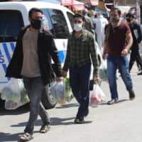 Men wearing protectice facemasks carry plastic bags as they shop at the covered bazaar in the historic Ulus district, in Ankara, on April 17, 2020 as the country adopts measures to curb the spread of the COVID-19 (the novel coronavirus). - Turkish Ministry of Internal Affairs announced that the curfew will be imposed for the second time between 18-19 April in 31 provinces with metropolitan status. | AFP-JIJI