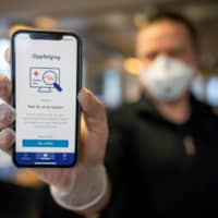 A man holds a smartphone showing a tracking and tracing app launched by the National Institute of Public Health to try to halt a return of the new coronavirus, on April 17, 2020 in Oslo. Norway, one of the first European countries to begin lifting confinement measures, is launching a smartphone tracking and tracing app that has been developed to provide health authorities a better picture of the spread of COVID-19 and tell users if they have been in contact with the disease. | AFP-JIJI
