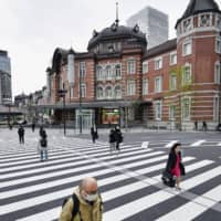 Masked people walk in front of Tokyo Station on Wednesday. | KYODO