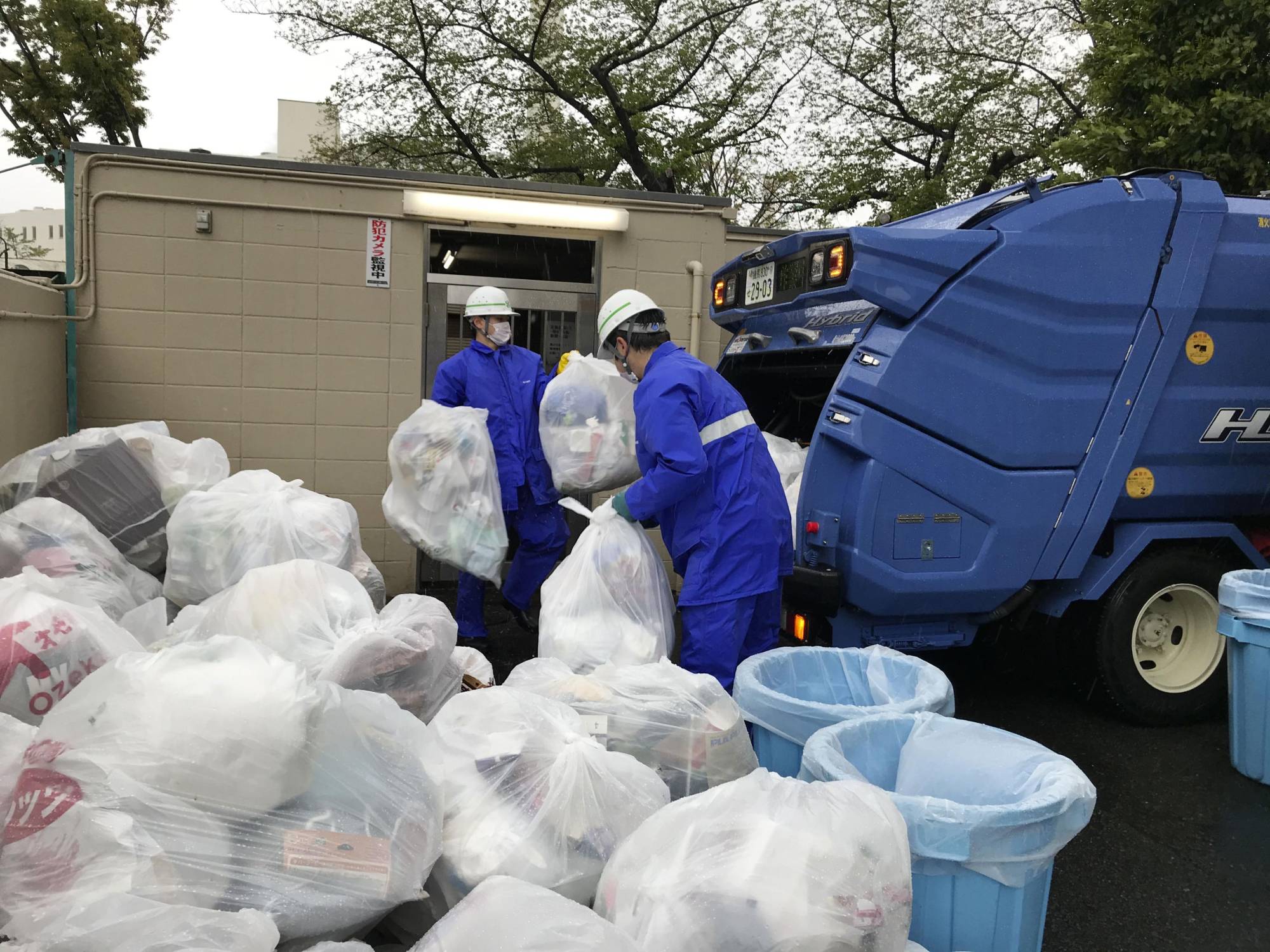 Workers pick up bags of waste in Tokyo on April 18.  | SEIICHIRO FUJII / VIA KYODO