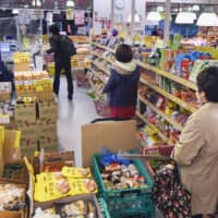 Customers keep their distance in lining up for the cashier at a supermarket in Tokyo\'s Nerima Ward on Wednesday. | KYODO 