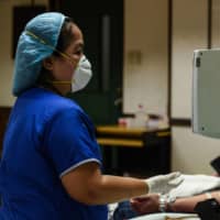 A nurse checks on a patient who has recovered from COVID-19 at a hospital in Manila on Wednesday. | AFP-JIJI