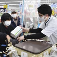 People buy boxes of masks at a drug store in Eiheiji, Fukui Prefecture, on Friday using tickets distributed to all Fukui households. | KYODO