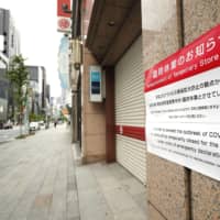 A temporary-closure notice is posted at the entrance of a major department store in Tokyo\'s Ginza shopping district on April12. | KYODO