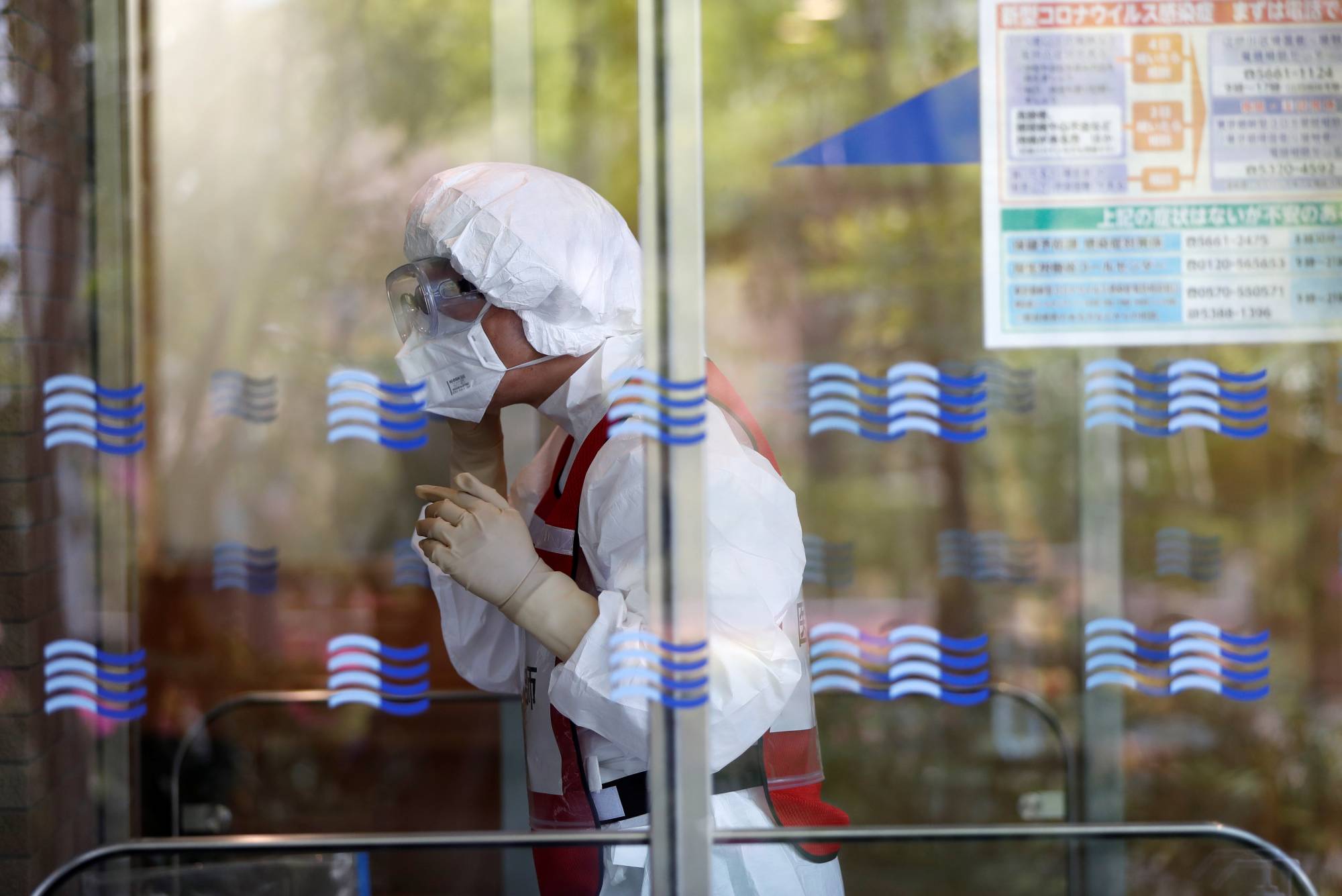A doctor wearing an N95 mask prepares a simulation for drive-thru polymerase chain reaction (PCR) tests for the new coronavirus in Tokyo's Edogawa Ward on Wednesday. The health ministry has unveiled a list of more than 10,000 medical clinics accepting new patients for online diagnoses in an effort to curb the spread of the virus among doctors and patients. | REUTERS