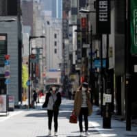 Empty streets: Women wearing face masks walk through a shopping district of Tokyo earlier this month. | REUTERS