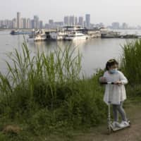 A child rides her push bike along the banks of the Yangtze River in Wuhan in China\'s Hubei province, on April 16. | AP