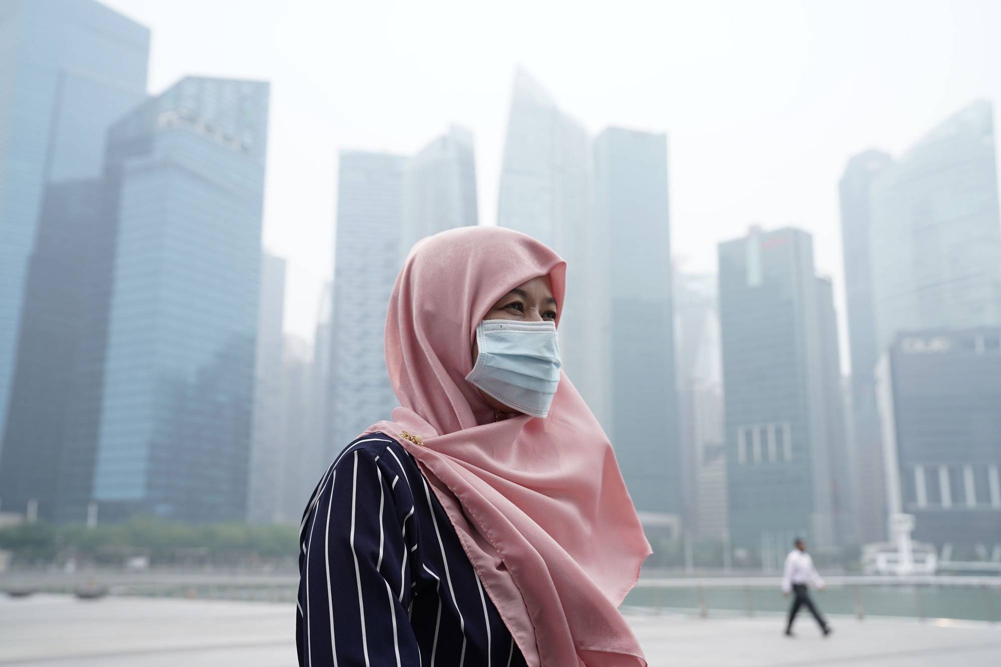A tourist wears a face mask as haze shrouds buildings in Singapore last September. | BLOOMBERG