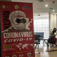 A COVID-19 sign is displayed in a departure terminal at Juanda International airport in Surabaya, East Java, on Friday.  | AFP-JIJI