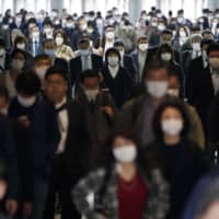 A Tokyo train station passageway is crowded with commuters during rush hour on Monday. | AP