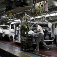 Nissan Motor Co. employees work on an assembly line at the company\'s plant in Fukuoka Prefecture. | REUTERS